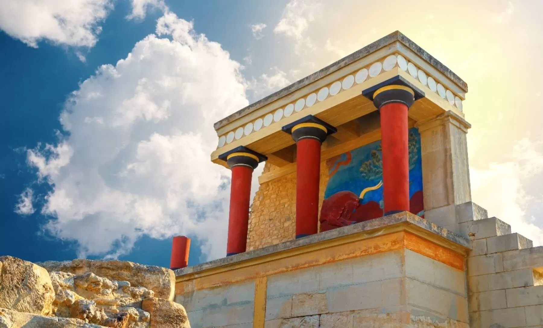Ανάκτορο της Κνωσού στην Κρήτη με κόκκινες κολόνες και μινωική τοιχογραφία υπό τον ήλιο