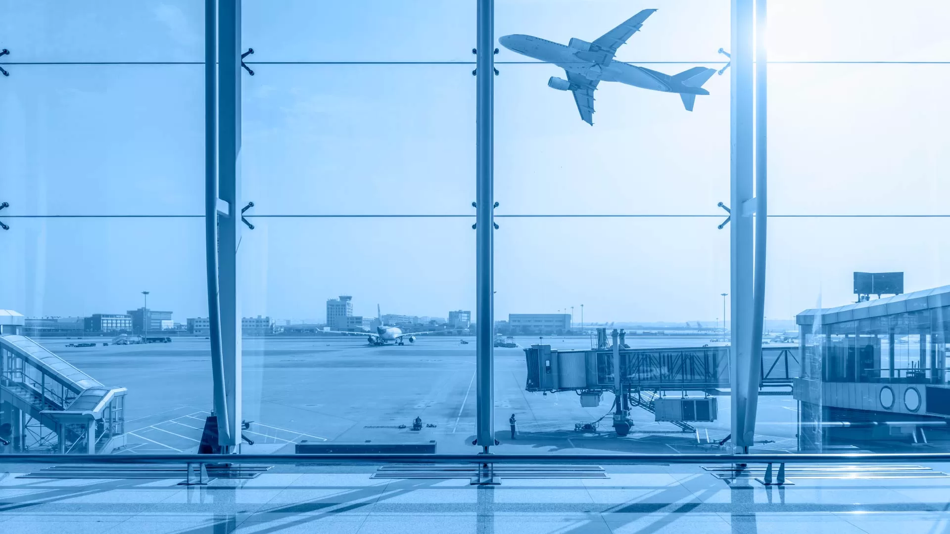 Αεροπλάνο απογειώνεται από αεροδρόμιο, όπως φαίνεται μέσα από το παράθυρο του τερματικού σταθμού, συμβολίζοντας την αεροπορική μεταφορά τουριστών.